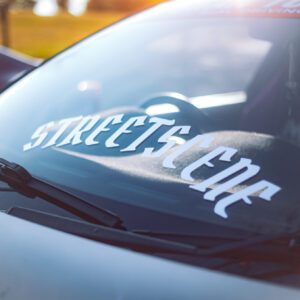 Windshield decal reading "STREETSCENE" on a car with windshield wipers visible.