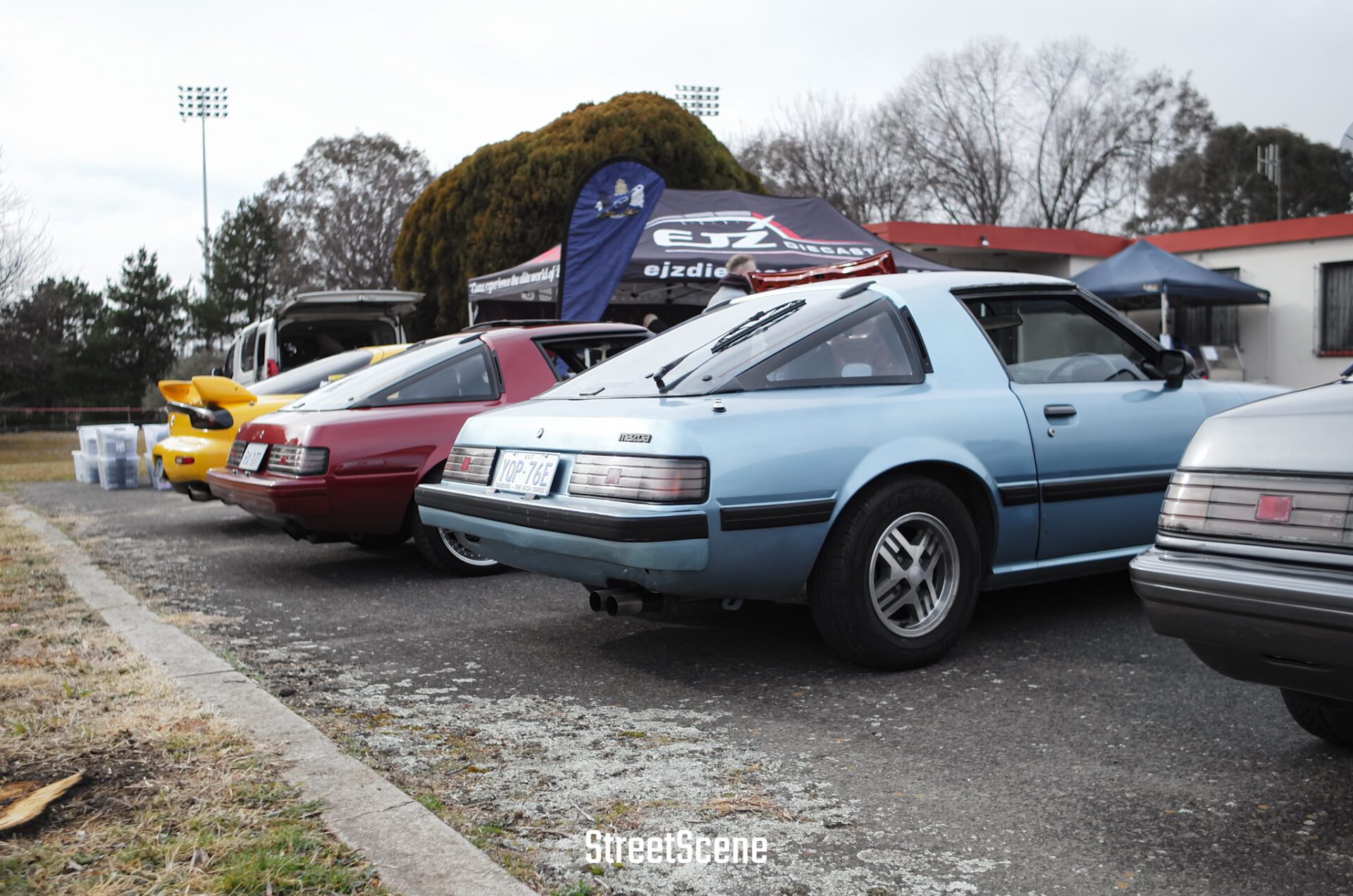 Rear view of a row of classic sports cars parked at an outdoor car show.